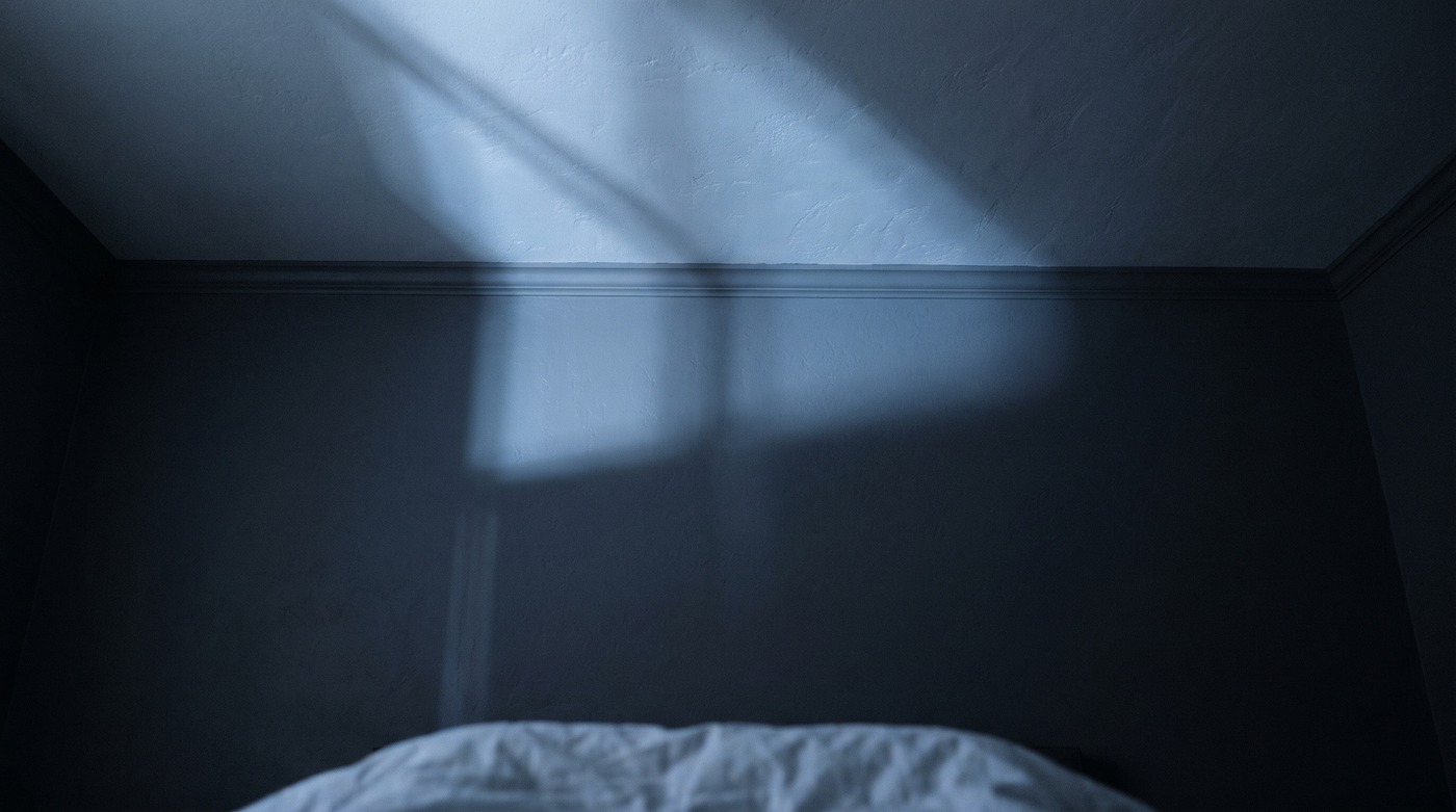 Plafond d'une chambre la nuit vu depuis le lit, ombre de fenêtre projetée par la lune